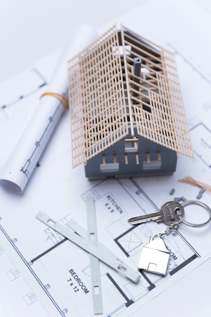 A model house on blueprints with a key to the new home close-up